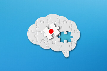 Japan learning concept, white jigsaw puzzle pieces with japan flag a human brain shape on blue background	
