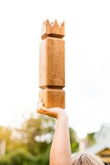 Kind spielt Wikingerschach (Kubb) hält König in der Hand. Child plays viking chess holds king in hand. Wooden Kubb King.