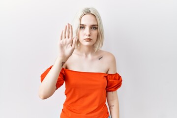 Young caucasian woman standing over isolated background doing stop sing with palm of the hand....