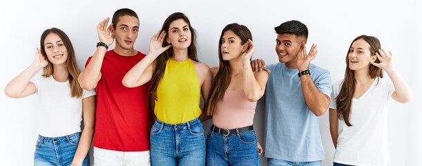 Group of people wearing casual clothes standing over isolated background smiling with hand over ear...