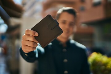 Young hispanic man smiling happy holding wallet at the city.