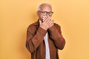 Senior man with grey hair wearing casual jacket and glasses shocked covering mouth with hands for mistake. secret concept.