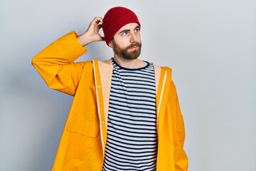 Caucasian man with beard wearing yellow raincoat confuse and wondering about question. uncertain...
