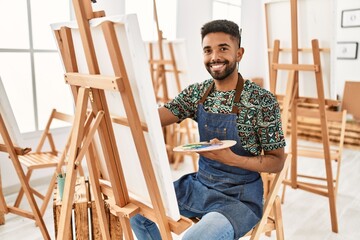 Young african american artist man smiling happy painting at art studio.