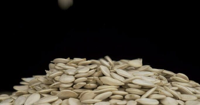 Falling grain onto a heap of pumpkin seeds. Rotating pile of grain. Isolated