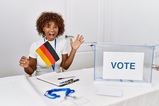 Young african american woman at political campaign election holding germany flag celebrating victory with happy smile and winner expression with raised hands