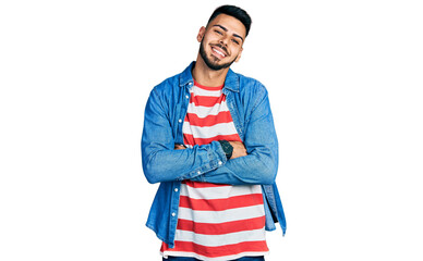 Young hispanic man with beard wearing casual denim jacket happy face smiling with crossed arms looking at the camera. positive person.