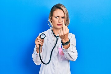 Beautiful young blonde doctor woman holding stethoscope showing middle finger, impolite and rude fuck off expression - obrazy, fototapety, plakaty