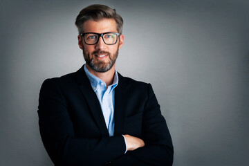 Handsome businessman wearing eyeglasses and suit while standing with arms crossed