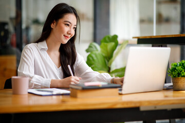 Fototapeta premium Portrait of smiling beautiful business asian woman with working in modern office desk using computer, Business people employee freelance online marketing e-commerce telemarketing concept.