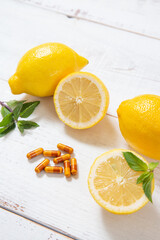 lemons and vitamin supplements on white wooden background
