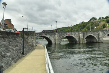 Obraz premium Promenade aménagée le long de la Meuse passant sous l'une des arches en pierres du pont de Jambes à Namur