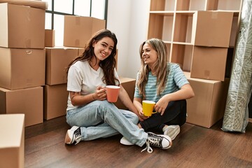 Young couple smiling happy drinking cup of coffee at new home.