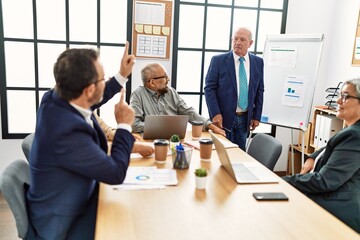 Group of middle age business workers listening boss conference during meeting at the office.