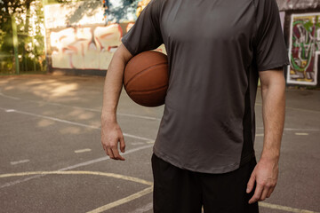 Fototapeta premium Young man playing with a basketball outdoors. Sports concept