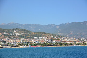 Naklejka na ściany i meble mediterranean town alanya with mountain and blue sky background, view from the sea to coastline