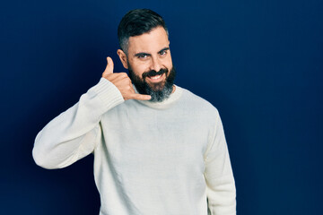 Young hispanic man wearing casual clothes smiling doing phone gesture with hand and fingers like talking on the telephone. communicating concepts.