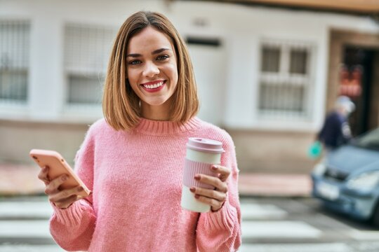 Young caucasian girl using smartphone and drinking coffee at the city.