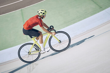 Top view of man in sports clothing cycling on track outdoors