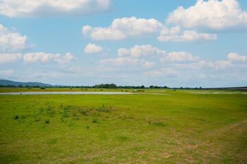 The landscape of green grass field and water reservoir with rail way bridge at Pa Sak Cholasit Dam, Lopburi, Thailand.