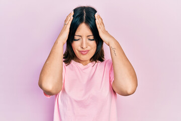 Young hispanic woman wearing casual pink t shirt suffering from headache desperate and stressed because pain and migraine. hands on head.
