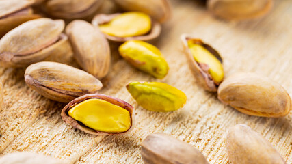 Roasted pistachios nuts. Fried and salty pistachios on wooden background. Close-up