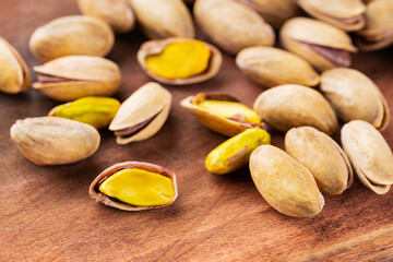 Roasted pistachios nuts. Fried and salty pistachios on wooden background. Close-up