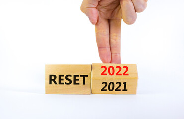 2022 reset new year symbol. Businessman turns a wooden cube and changes words 'Reset 2021' to...