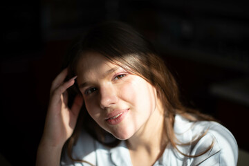 Fashion lifestyle image of pretty teenage young woman sitting in kitchen. Natural beauty.