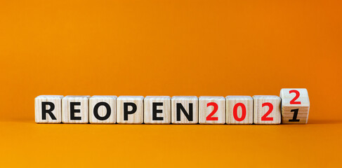 2022 reopen new year symbol. Turned a wooden cube and changed words 'Reopen 2021' to 'Reopen 2022'. Beautiful orange background, copy space. Business, 2022 reopen new year concept.