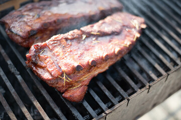 grilling baby back pork ribs over flaming grill.