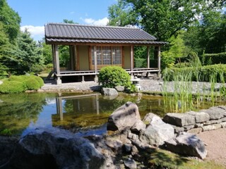 Fototapeta na wymiar St. Petersburg, Russia - July 4, 2021. Peter the Great Botanical Garden. A tea house in the Japanese garden of the architect and designer Yamada Midori near an artificial pond on a sunny summer day.
