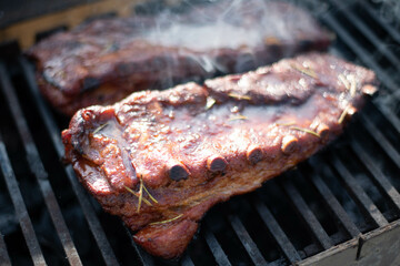 grilling baby back pork ribs over flaming grill.