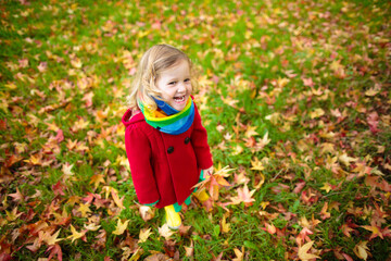 Little girl playing with maple leaf in autumn