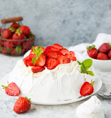 Pavlova cake with meringue and fresh strawberries on a light background, selective focus