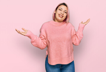 Hispanic woman with pink hair wearing casual winter sweater clueless and confused expression with...