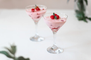 Homemade cheesecake slice with fresh raspberries and mint leaves on white plate on the table. Healthy organic summer dessert
