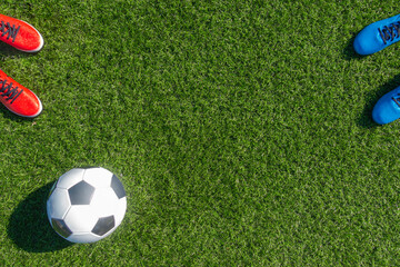 Soccer football background. Soccer ball and two pair of football sports shoes on artificial turf...