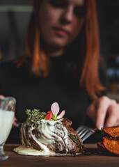 woman with fork and knife eating beef steak in cafe. focus on meat