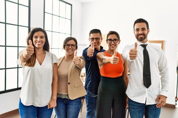 Group of business workers smiling happy doing ok sign with thumbs up at the office.