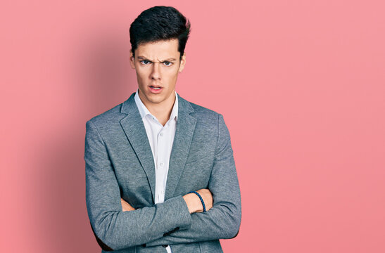 Young hispanic business man with arms crossed gesture in shock face, looking skeptical and sarcastic, surprised with open mouth