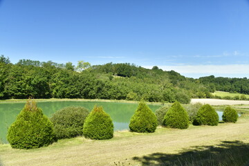 L'étang aux eaux émeraudes entre forêt et prairie sous un ciel d'été près du Bourg de Champagne au Périgord Vert