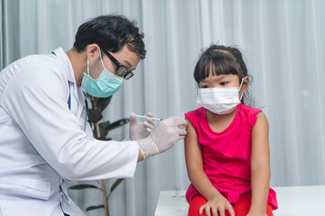 Fototapeta na wymiar Asian doctor injection vaccine for protecting virus covid-19 to a girl wear medical mask,People are Girls are vaccinated against influenza every year.