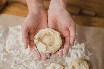 The baker's woman's hands are holding the dough. Close-up