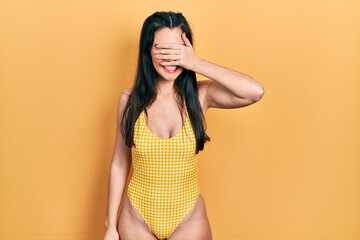 Obraz premium Young hispanic girl wearing swimsuit smiling and laughing with hand on face covering eyes for surprise. blind concept.