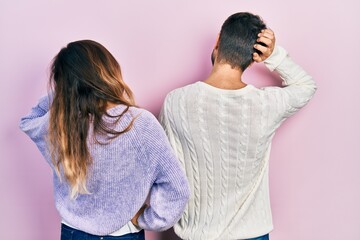 Young hispanic couple wearing casual clothes backwards thinking about doubt with hand on head