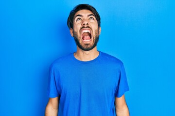 Young hispanic man wearing casual clothes angry and mad screaming frustrated and furious, shouting with anger. rage and aggressive concept.