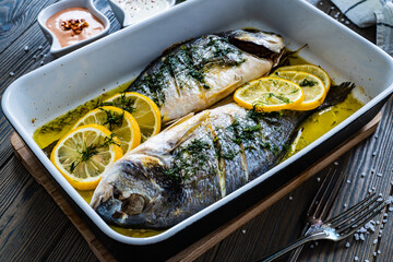 Roast sea bream  in cooking pan on wooden table

