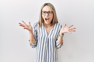 Asian young woman wearing casual clothes and glasses crazy and mad shouting and yelling with aggressive expression and arms raised. frustration concept.
