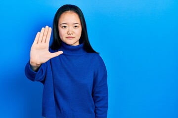 Young chinese girl wearing casual clothes doing stop sing with palm of the hand. warning expression...